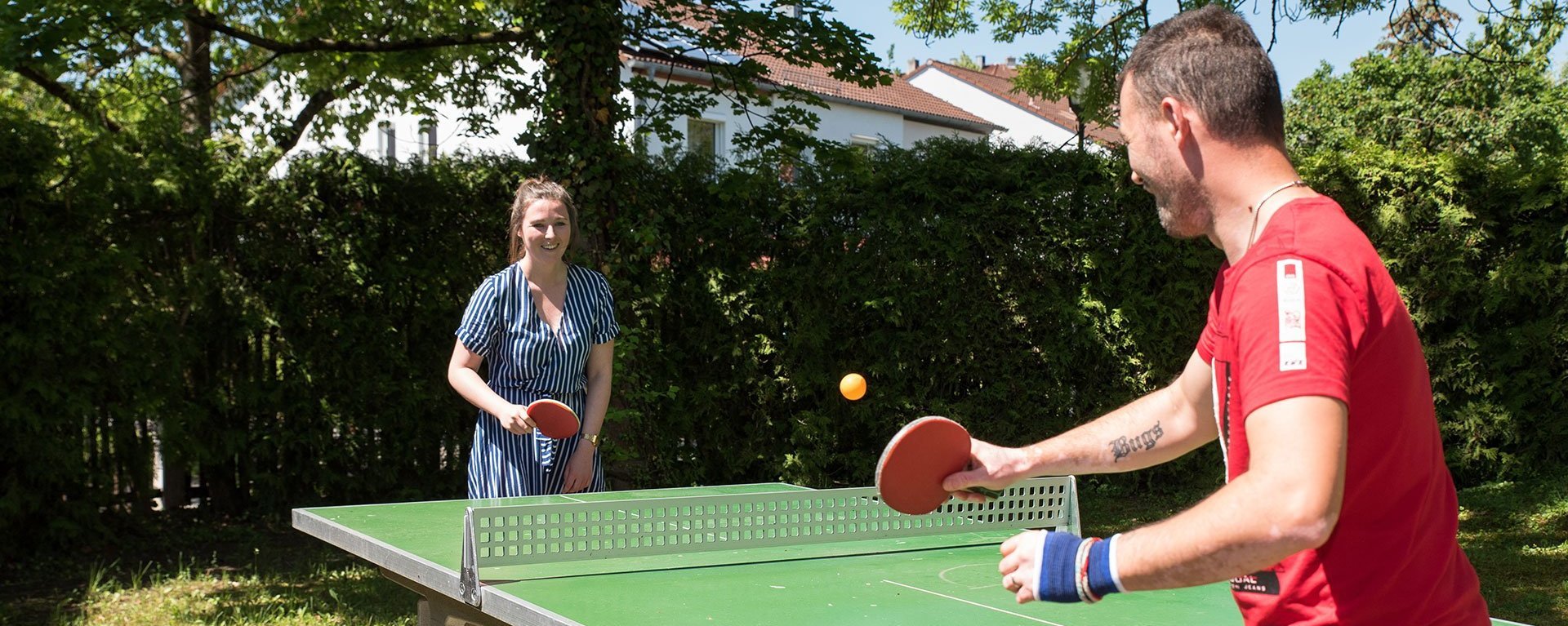 Eine Frau und ein Mann beim Tischtennis im Garten