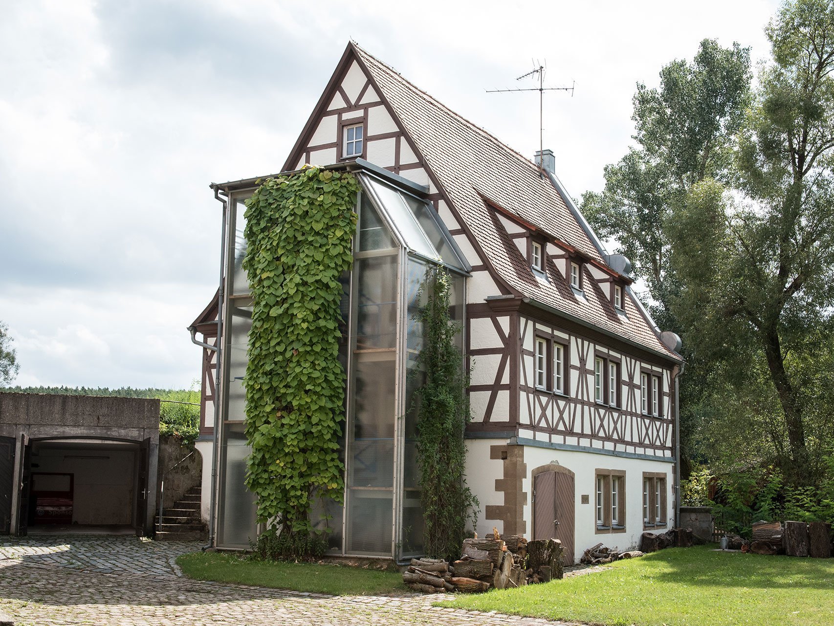 Ein hübsches Fachwerkhaus mit Grünanlage - an einer Seite wächst Efeu bis fast zum Dach