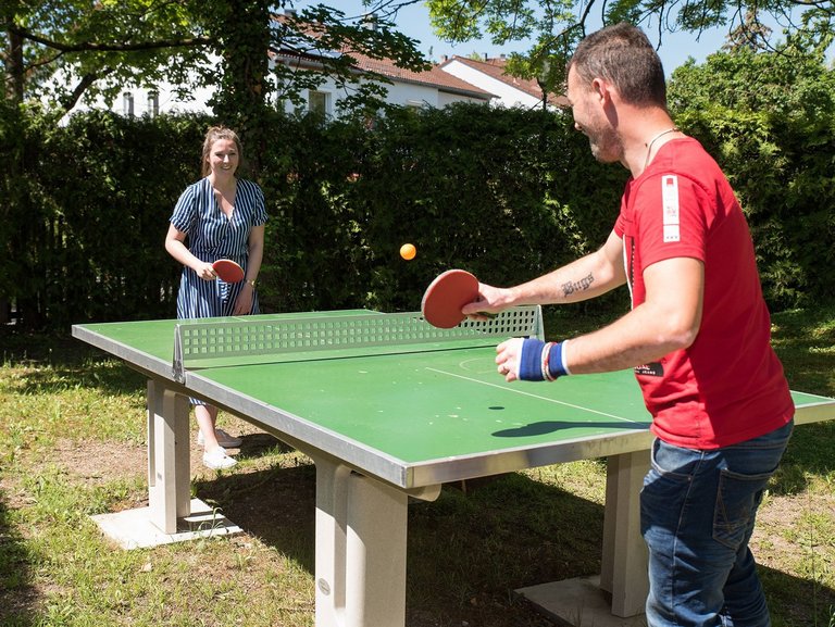 Eine Frau und ein Mann beim Tischtennis im Garten